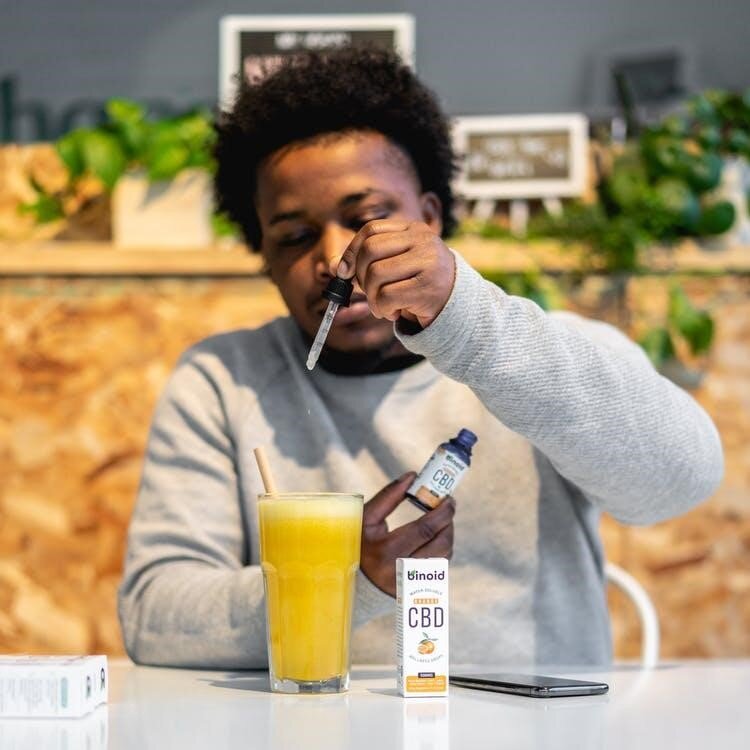 A young man uses CBD oil in his drink